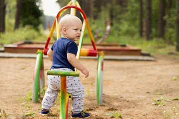 Happy baby boy having fun on a swing on summer day