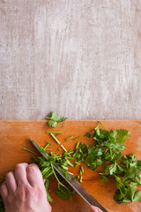 Cut into pieces batch of parsley on wooden desk. Herbs as healthy and organic food, top view of cooking process, free space above