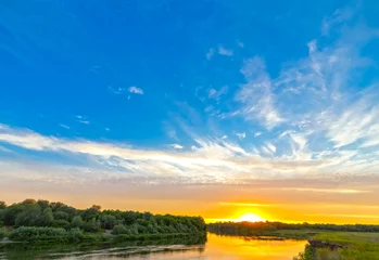 Foto op Canvas Bright sunset and the blue sky above the river. © VASILEVS