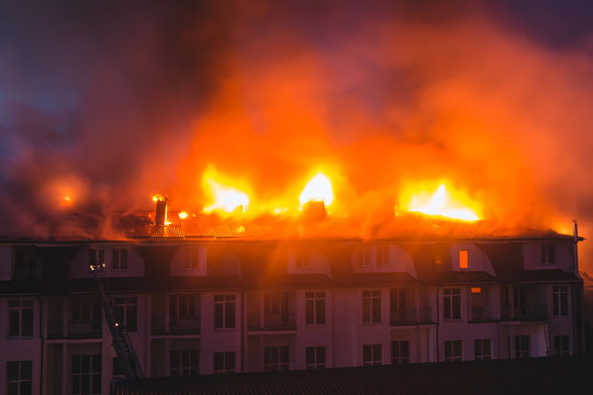 Building in fire at the night , burning fire flame with smoke on the apartment house roof
