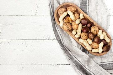 Mixed nuts in a bowl on a white wooden surface. Copy space