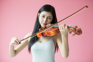 beautiful girl playing the violin on pink background