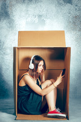Introvert concept. Woman sitting inside box and working with phone
