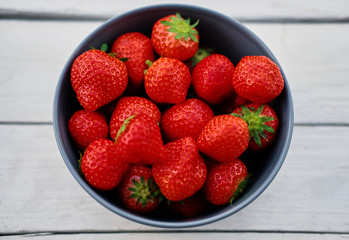 Delicious strawberry in a cup on a wooden desk.
