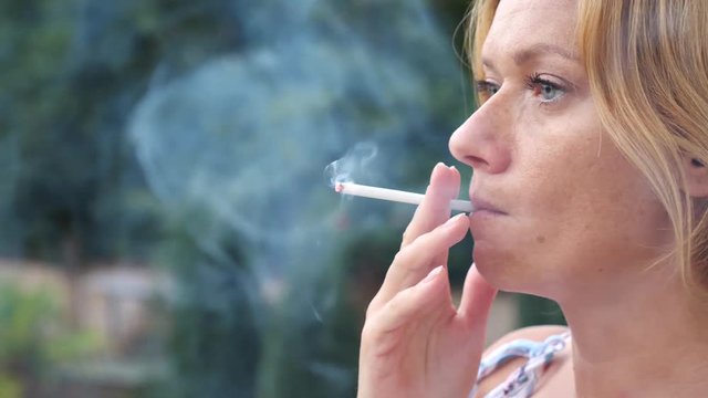A woman smokes in the summer on the street thin cigarettes. 4 . Slow-motion