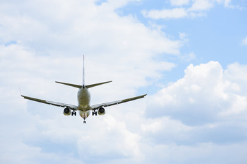 Passenger airplane in the clouds rear side view