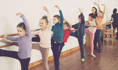 cheerful children rehearsing ballet dance in studio