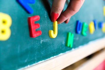 womans finger hold a letter by the school blackboard