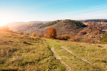 View on the beautiful colorful autumn landscape of the hills with trees and greenfields in the countryside