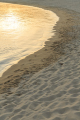 Soft sea wave on sandy beach, Beautiful Greek beach on sunset, Close up photo of sandy beach with reflecting sunset