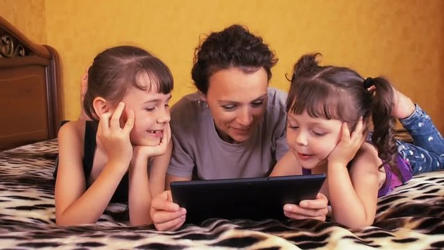 Mom and children laugh at the tablet. Family with a tablet.