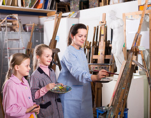 Skillful woman teacher showing her skills during painting class at art studio