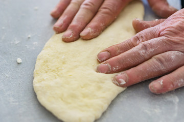 Close-up of the rough hands of a woman preparing dough mills. Shallow depth of focus. Concept of home coziness.