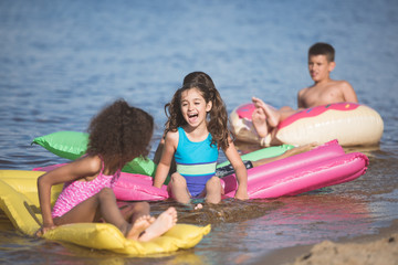 Fototapeta premium happy little kids have fun on inflatable mattresses at seaside