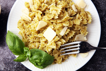 Farfalle pasta bows with pesto on a plate on a rustic background