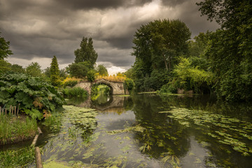 English historic medieval bridge overlooking river Avon beside Warwick Castle with lush green...