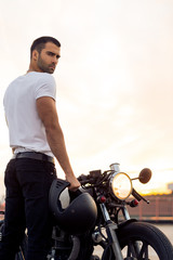Sporty biker handsome rider man in white t-shirt want to ride his classic style cafe racer...