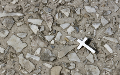 A Christian metal cross against a background of stone crumbs. Religious symbol. Catholicism,...