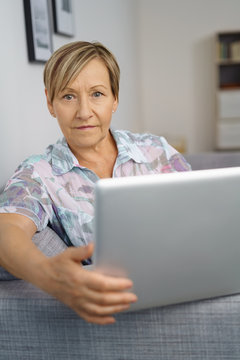 moderne ältere frau sitzt auf dem sofa und arbeitet am laptop