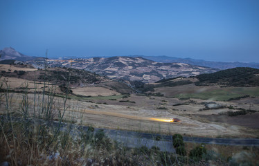 Mountain landscape at dusk with combine harvester working