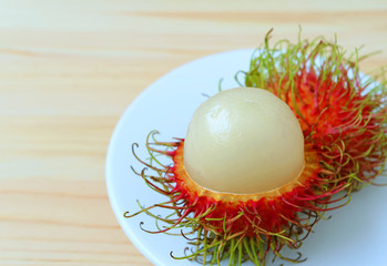 Close-up of Juicy White Fresh Ripe Rambutan Fruit on White Plate and Wooden Table 