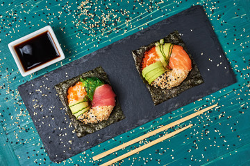 Sushi donuts on wooden board with ginger on black background
