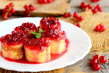 Sweet pancakes with redcurrant jam. Home pancakes rolls with redcurrant jam and a mint leaf on a white plate and an old wooden table. Delicious summer breakfast. Rustic style