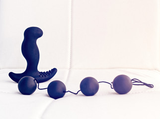 Sex toys (prostate massager and anal balls) on a leather background