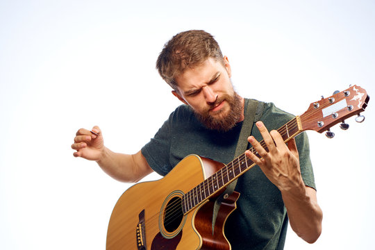 Man with beard on white isolated background playing guitar, strings
