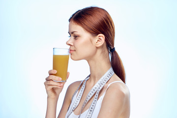 Young beautiful woman on a blue background holds a glass of fresh juice, diet, fitness