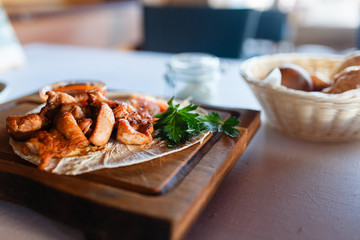 Grilled meat dish meat grill, soum and fresh herbs on a wooden plate and a wooden stand.