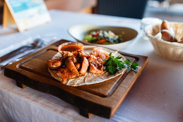 Grilled meat dish meat grill, soum and fresh herbs on a wooden plate and a wooden stand.