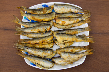 Fried baltic herring on a plate on wooden background