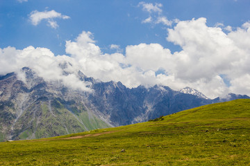 Rocky Caucasus mountains in Kazbeki region with cloudy blue sky background
