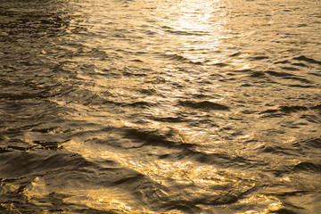 Water surface with ripples and sunrays reflections