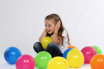 Fototapeta na wymiar Kleines Mädchen sitzt zwischen Ballons und hält sich die Ohren zu