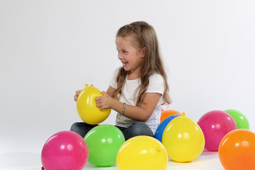 Fototapeta na wymiar Kind sitzend zwischen Ballons lacht