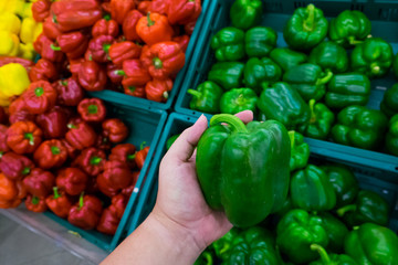 consumerism and people concept - man buying bell peppers or paprika at grocery store