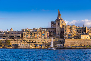 Fototapeta premium Valletta, Malta - Saint Paul's Cathedral and the ancient walls of Valletta with sail boat in the morning