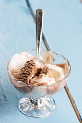 Vanilla and chocolate ice cream in the crystal bowl on the wooden planks