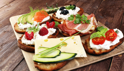 Bread Brushetta or authentic traditional spanish tapas set for lunch table. Sharing antipasti on party or summer picnic time over wooden rustic background.