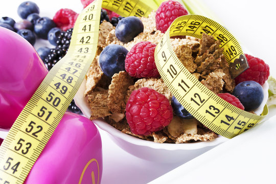 bowl of cereal with natural fruits and tape measure, concept of diet