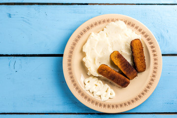 Flat lay mashed potatoes served with fish meat sticks on the plate