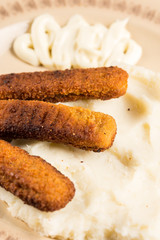 Flat lay mashed potatoes served with fish meat sticks on the plate