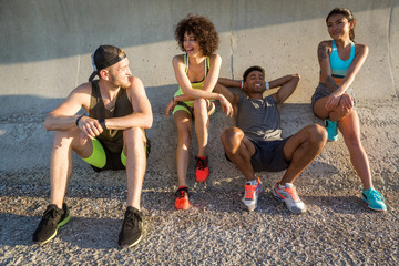 Group of young friends in sportswear resting and talking outdoors