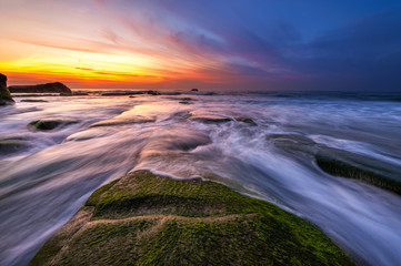 vibrant sunset with green moss at Kudat Sabah Malaysia. Image contain soft focus due to long exposure.