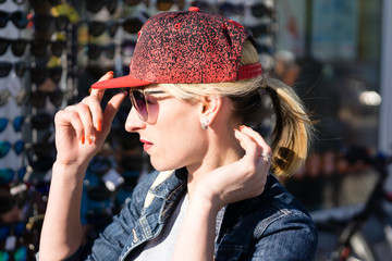 Woman is trying on baseball cap outdoors
