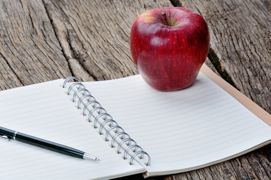 Notepad with pen and apple fruit on table