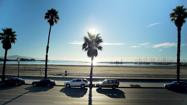 Wide shot of beach with a running and cars driving by