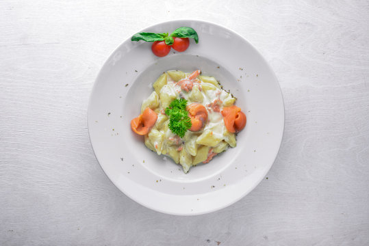 Potato dumplings with salmon and vegetables. On a wooden background. Top view. Free space for text.